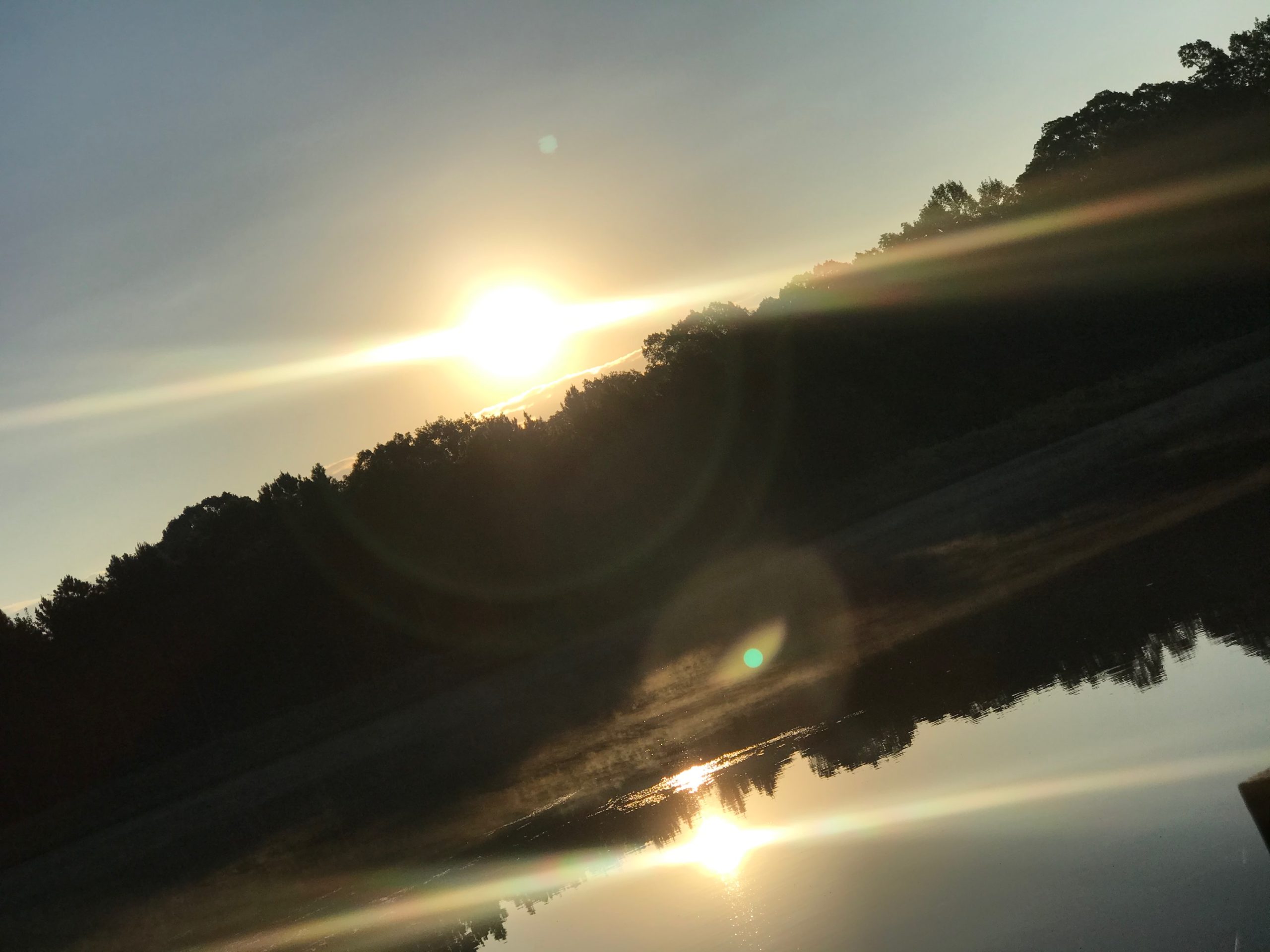 Reflection of rising sun in lake taken at an angle to see sun rays